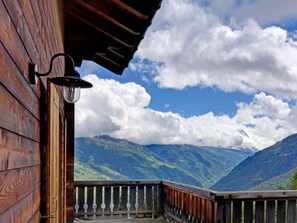 Un balcone in legno con ringhiera in metallo affacciato su un paesaggio montuoso.