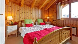 A wooden-paneled bedroom with a bed, two bedside tables, and a window.