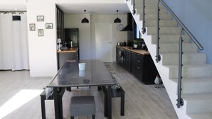 Et moderne køkken med et langt spisebord, en trappe og udsigt til opholdsstuen.
