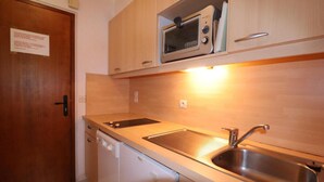 Cozinha compacta com micro-ondas, pia e lava-louças.