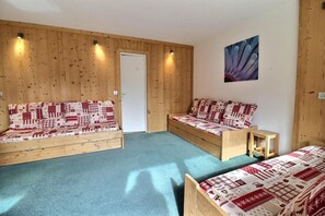 A room with two wooden beds, a door, and a wall-mounted artwork. - 10m from ski slopes, 1st floor, balcony, 27m², Méribel-Mottaret (Méribel - Les Allues)