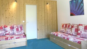 Quarto com duas camas de madeira, cada uma com roupa de cama estampada em vermelho e branco.