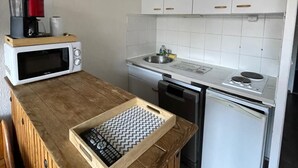 Una cocina compacta con armarios blancos, un microondas, un fregadero y una estufa.