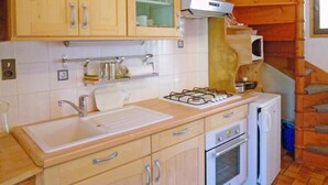 A compact kitchen with wooden cabinets, a gas stove, a sink, and a small oven.