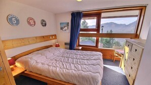 A bedroom with a wooden bed, a dresser, and a window with a mountain view. - 50m from ski slopes, Ground floor, balcony, tv, 40m², Peisey-Vallandry (Landry)