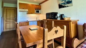 A compact kitchen with wooden cabinets, a microwave, and a coffee maker on the counter. - 10m from ski slopes, floor -3, balcony, tv, ski locker, 35m², Les Menuires (Les Menuires)