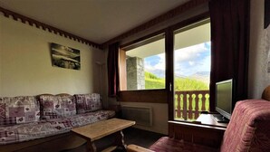 A cozy room with a wooden bench, a cushioned sofa, and a television on a wooden stand. - 10m from ski slopes, floor -3, balcony, tv, ski locker, 35m², Les Menuires (Les Menuires)