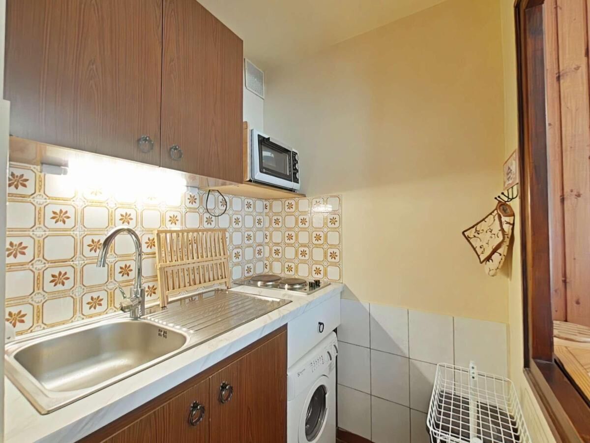 A compact kitchen with a sink, microwave, and washing machine.