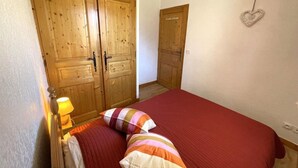 A bedroom with a bed, pillows, a nightstand, a lamp, and wooden wardrobes.