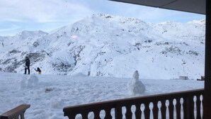 A snowy mountain landscape with a wooden railing in the foreground.