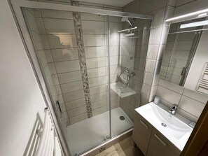 A modern bathroom with a glass-enclosed shower, a white sink, and a mirror. - 10m from ski slopes, floor -2, balcony, tv, ski locker, 35m², Les Menuires (Les Menuires)