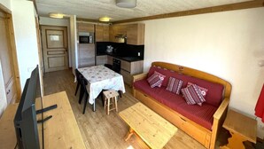 A compact living space with a kitchenette, a dining area, and a sofa.