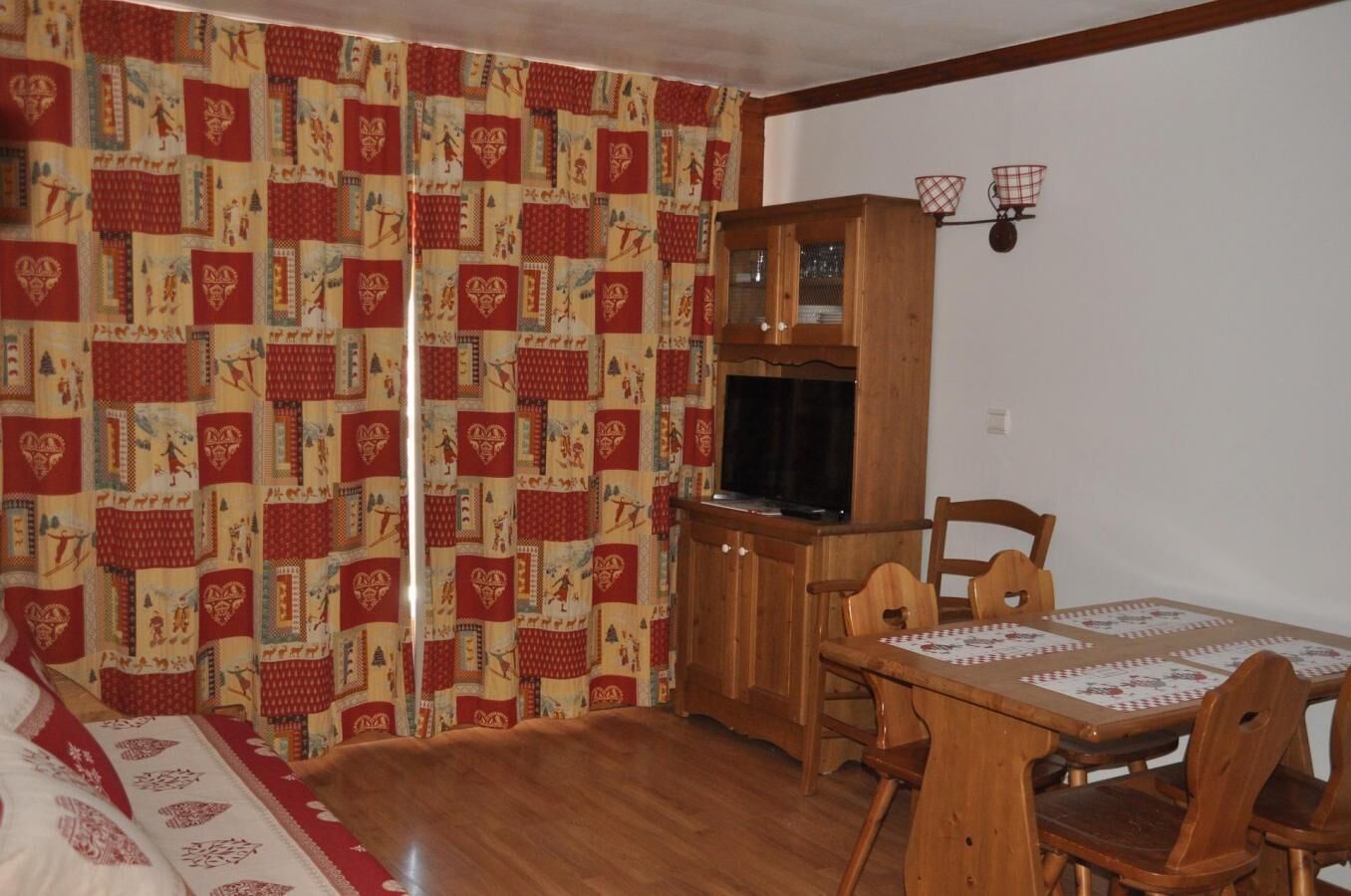 A cozy room with a wooden dining table, chairs, a television, and a cabinet.