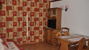 Une pièce chaleureuse avec une table à manger en bois, des chaises, un téléviseur et un meuble.