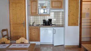Une cuisine compacte dotée de meubles en bois, d’un four à micro-ondes, d’une machine à café et d’un lave-vaisselle.
