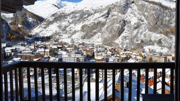 Une ville de montagne enneigée, avec des bâtiments et une vue dégagée sur les montagnes.