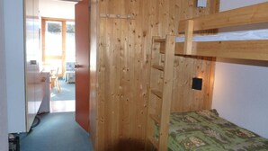Een slaapkamer met stapelbedden, een houten wand, een bureau en een stoel op de achtergrond.