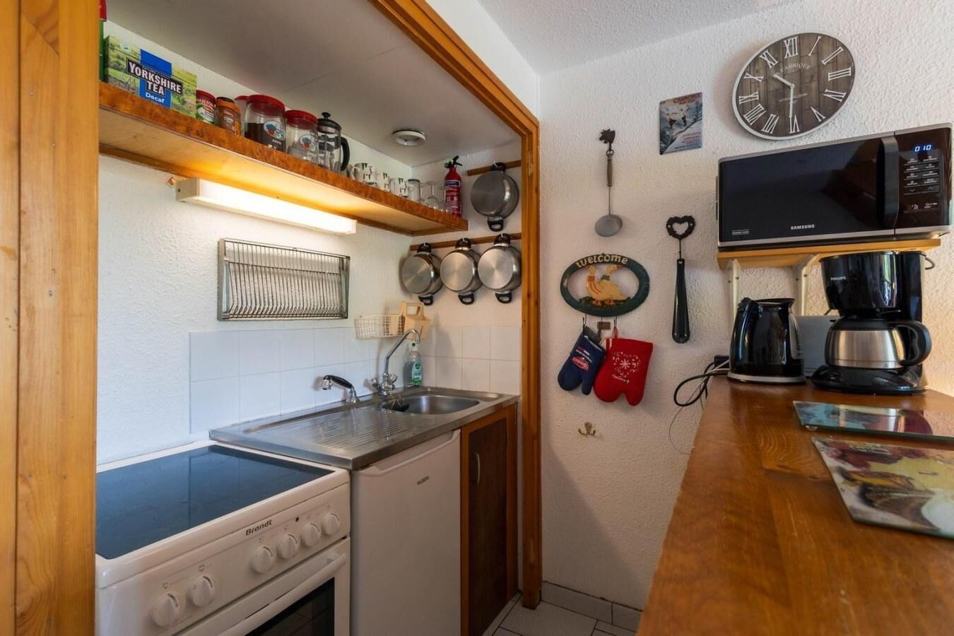 Une cuisine de taille réduite équipée d’une cuisinière, d’un évier et d’une machine à café.