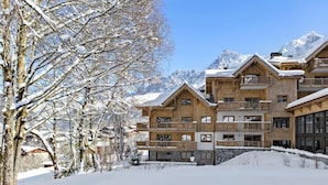 A multi-story wooden chalet with balconies, surrounded by snow-covered trees and mountains. - Wifi, view mountain, fitness, swimming pool, sauna, hammam, balcony, tv, ski locker, 55m² (Les Houches)