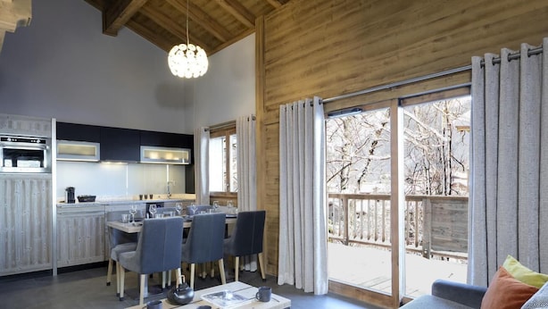 A modern kitchen with a dining area, a sofa, and a large sliding glass door leading to a balcony. - Wifi, view mountain, fitness, swimming pool, sauna, hammam, balcony, tv, ski locker, 55m² (Les Houches)