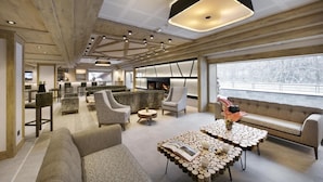 A modern lounge area with sofas, armchairs, and a coffee table with a unique design. - Wifi, view mountain, fitness, swimming pool, sauna, hammam, balcony, tv, ski locker, 55m² (Les Houches)