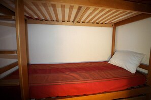 A single wooden bunk bed with a red mattress and a white pillow. - 20m from ski slopes, 2nd floor, balcony, tv, ski locker, 35m², Tignes (Tignes)