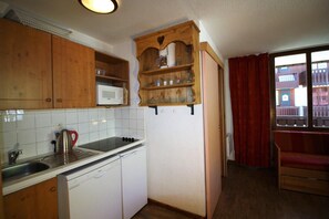 A compact kitchen with wooden cabinets, a microwave, a kettle, and a dishwasher. - 20m from ski slopes, 2nd floor, balcony, tv, ski locker, 35m², Tignes (Tignes)