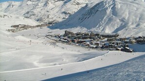 Een bergstad bedekt met sneeuw, met skipistes en gebouwen.