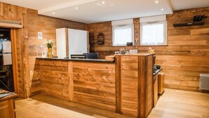 A wooden interior with a reception desk, wooden cabinets, and a window with curtains. - Parking, tv, ski locker, 35m², La Norma (Avrieux)