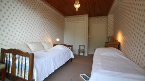 Quarto com duas camas, teto de madeira e papel de parede estampado.