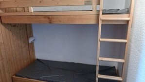A bunk bed with a wooden ladder and a mattress.