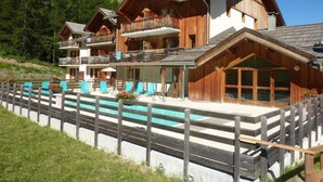 Un chalet en bois doté d’une piscine, de balcons et offrant une vue sur la forêt environnante.