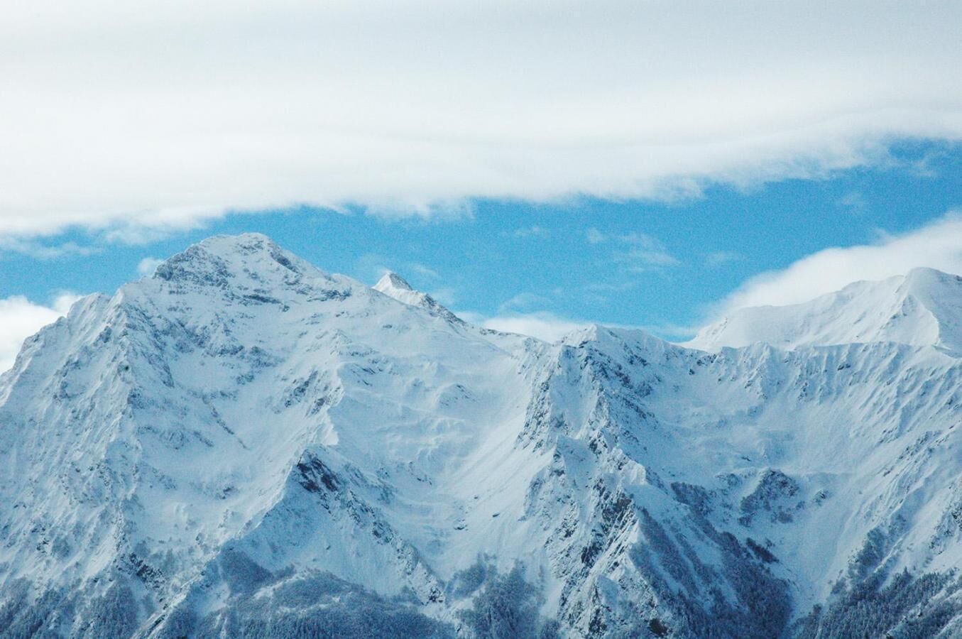 A snow-covered mountain range with rugged peaks and a clear sky.