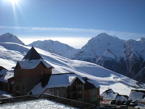 A snow-covered mountain with a wooden building featuring a steep roof and a stone archway.