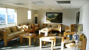 A spacious room with wooden furniture, large windows, and a painting on the wall.