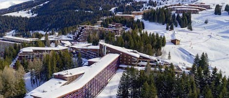 A ski resort with multiple buildings, including a large hotel with a curved facade and a smaller lodge.