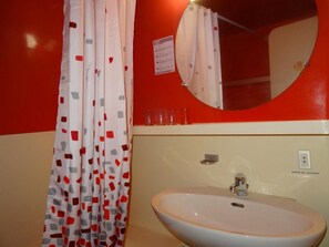 A bathroom with a white sink, red walls, and a mirror above the sink.
