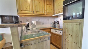 A kitchen with wooden cabinets, a stainless steel sink, a coffee maker, and a Bosch dishwasher. - 10m from ski slopes, 5th floor, balcony, 33m², Méribel-Mottaret (Méribel - Les Allues)