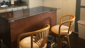 A kitchen with a central island, two wicker chairs, a refrigerator, and a microwave. - The Lucky Buc-Pet friendly cottage perfect for a couple or small family. (Ocracoke)