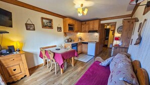 A cozy room with a bed, a dining table with chairs, a kitchen area, and a wooden cabinet. - 10m from ski slopes, Ground floor, view mountain, balcony, tv, ski locker, 30m², Les Menuires (Les Menuires)