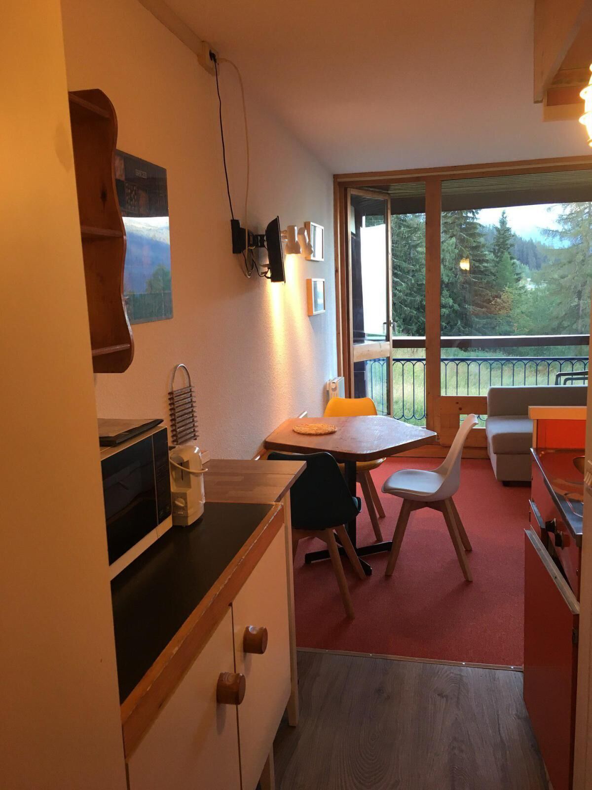 A compact kitchen with a dining area, a view of the outdoors, and a small seating area.