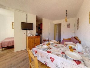 A cozy room with a dining table set for four, a television mounted on the wall, and a bed with a patterned bedspread. - 2nd floor, balcony, tv, ski locker, 27m², Les Menuires (Les Menuires)