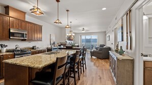 A spacious kitchen with a large island, wooden cabinets, and a view to the outside. - Master Suite w/Lake Views - Seasons at Sandpoint (Sandpoint)