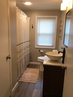 Een bad/douchecombinatie, een haardroger, handdoeken, zeep