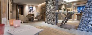 A modern hotel lobby with a stone accent wall, a reception desk, and comfortable seating.