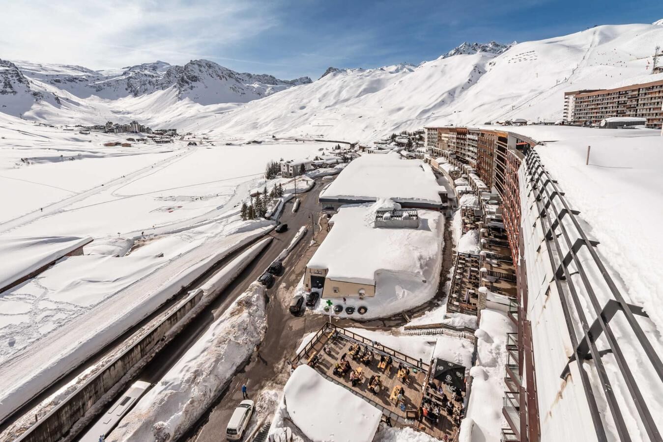 A snow-covered mountainous area with a ski resort, including a building with multiple floors and a parking area.