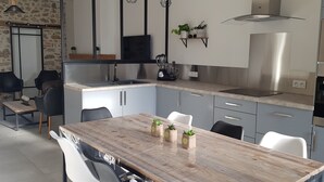 Ett modernt kök med ett matbord i trä, grå skåp och vitvaror i rostfritt stål.