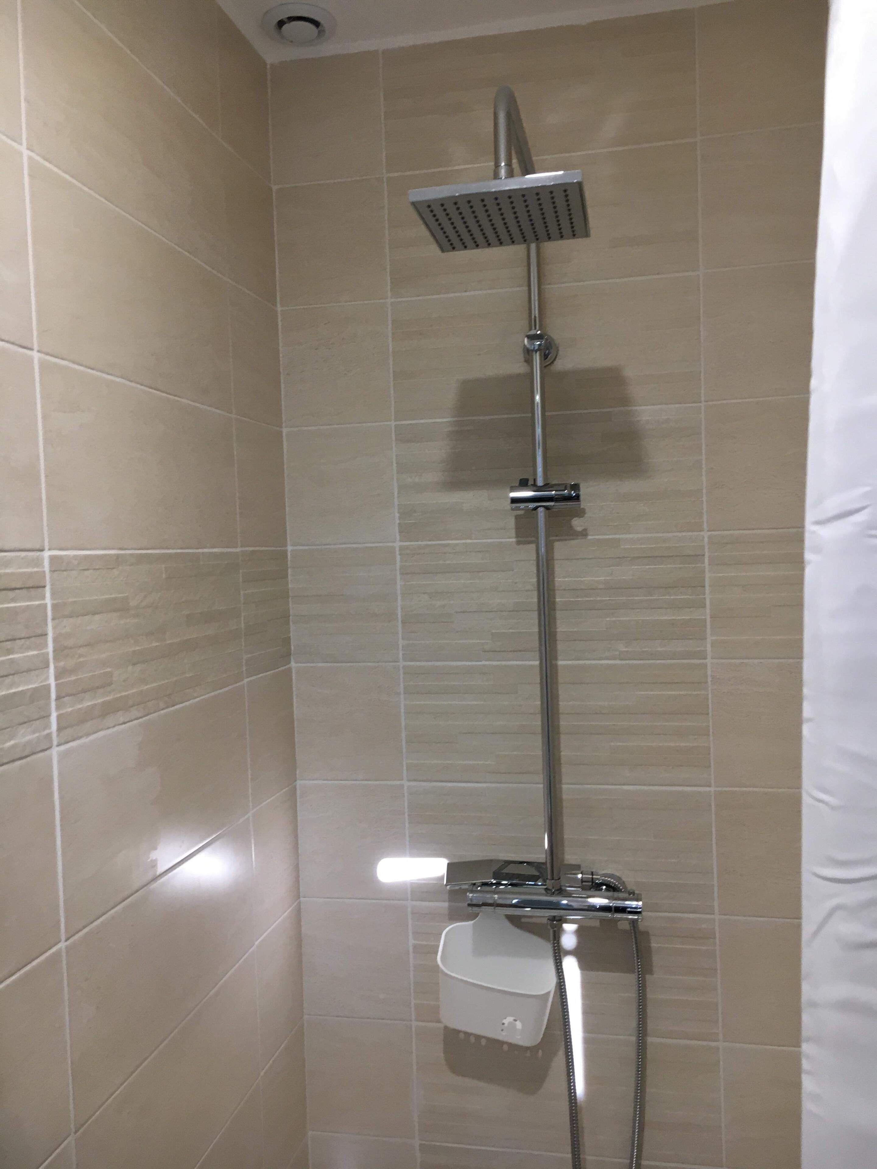 Eine Dusche mit Handbrause und einer fest installierten Bedienfeld.