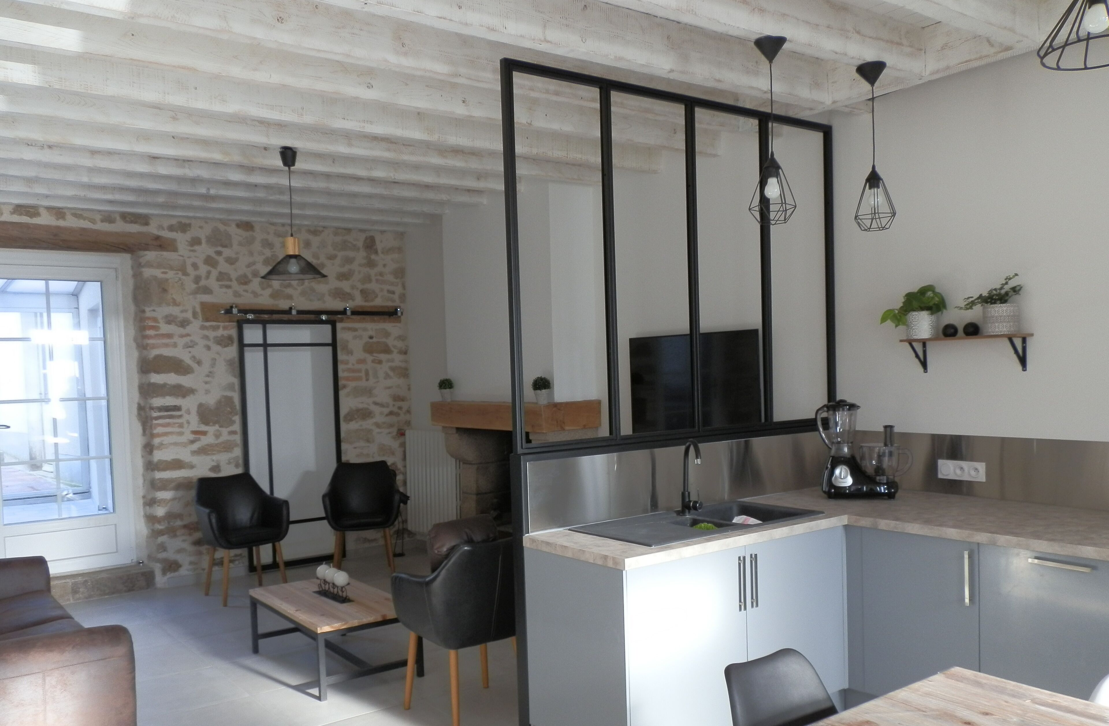 Eine moderne Küche mit einer Steinwand, schwarzen Stühlen, einem Holztisch und einem Fernseher.