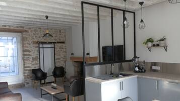 Eine moderne Küche mit einer Steinwand, schwarzen Stühlen, einem Holztisch und einem Fernseher.